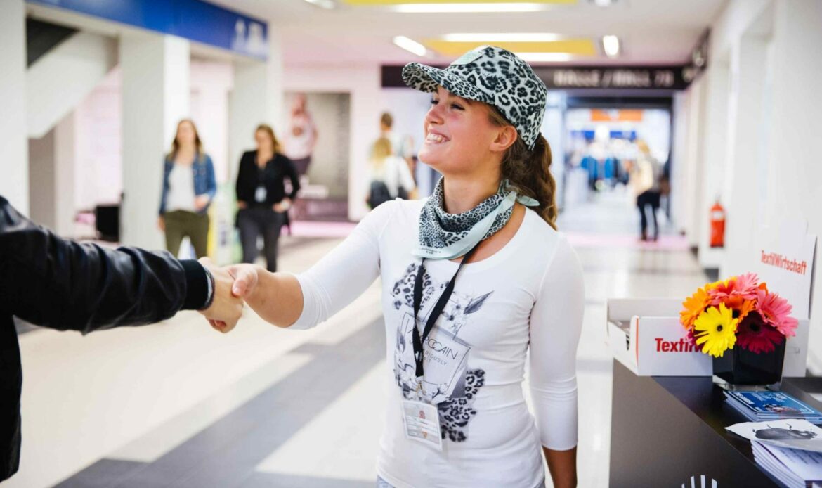 Junge Frau mit Outfit von Marc Cain arbeitet in als Promoterin und gibt jemandem die Hand