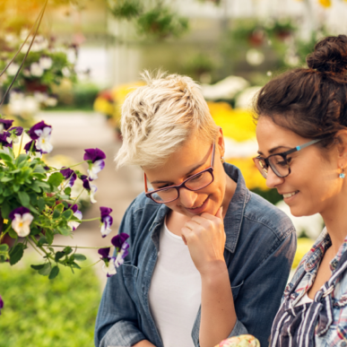 Zwei Frauen mit bunten Pflanzen in einem Gewächshaus