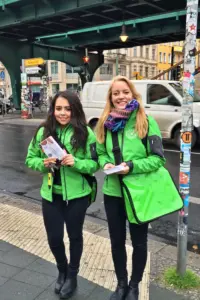 Zwei Promoter:innen bei der Arbeit in grüner Kleidung auf der Straße